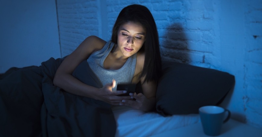 A woman checking her phone to read Facebook at night